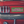 Load image into Gallery viewer, Green and cream checkerboard bumper sticker with pink text with song lyric, on a red car.

